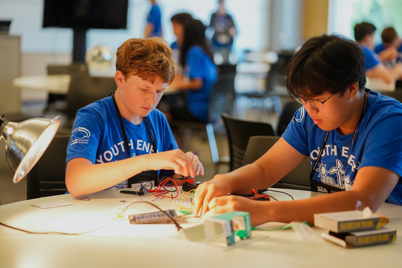 two male y.e.s. students sitting at a table working with concentration